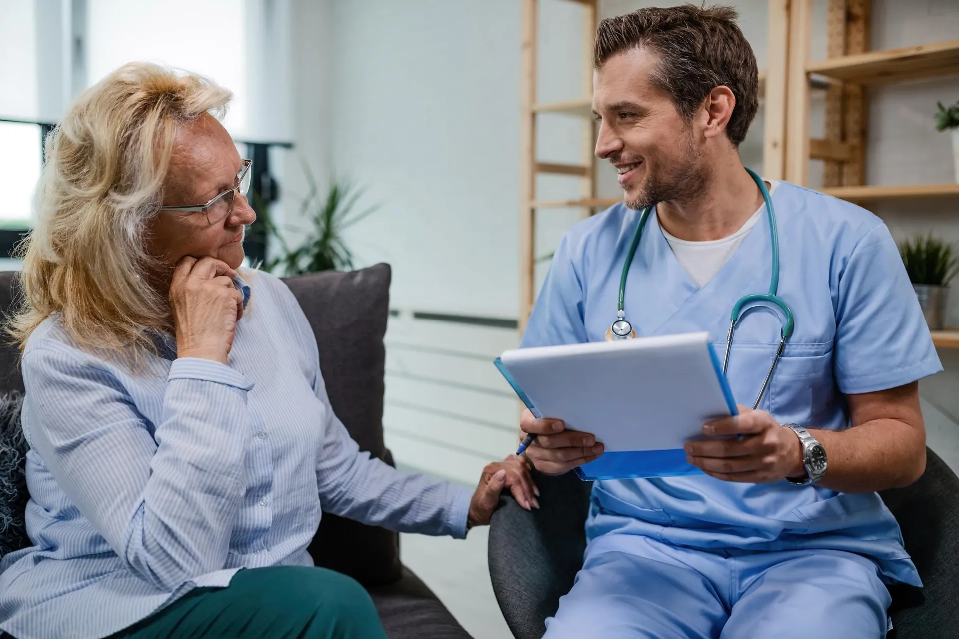 Médico revisando documentación médica con una paciente en su casa